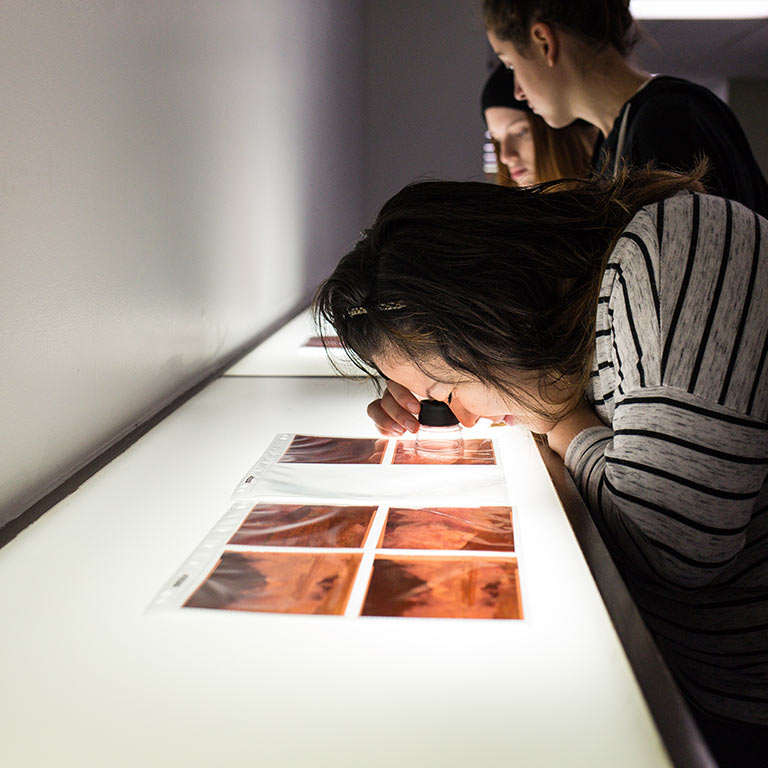 Photo students view prints on a light box. 