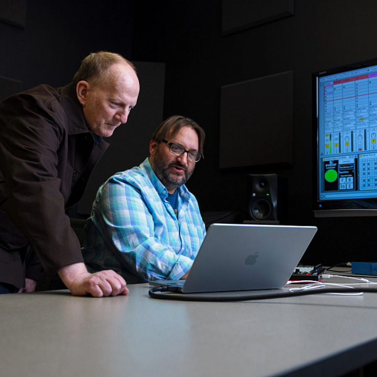 Herron professors Scott Deal (left) and Jason Palamara (right) look at a laptop screen together