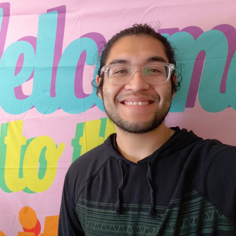 A selfie of Juan Villalva smiling in front of a colorful backdrop.