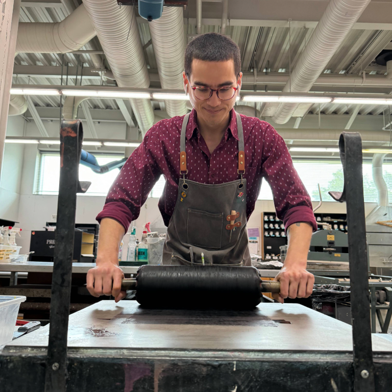 Herron School of Art and Design printmaking shop technician Jager Palad rolling black to prepare for a print
