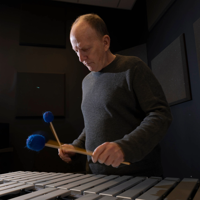 Photograph of Herron School of Art and Design Professor of Music Technology Scott Deal looking down while playing the vibraphone with mallets